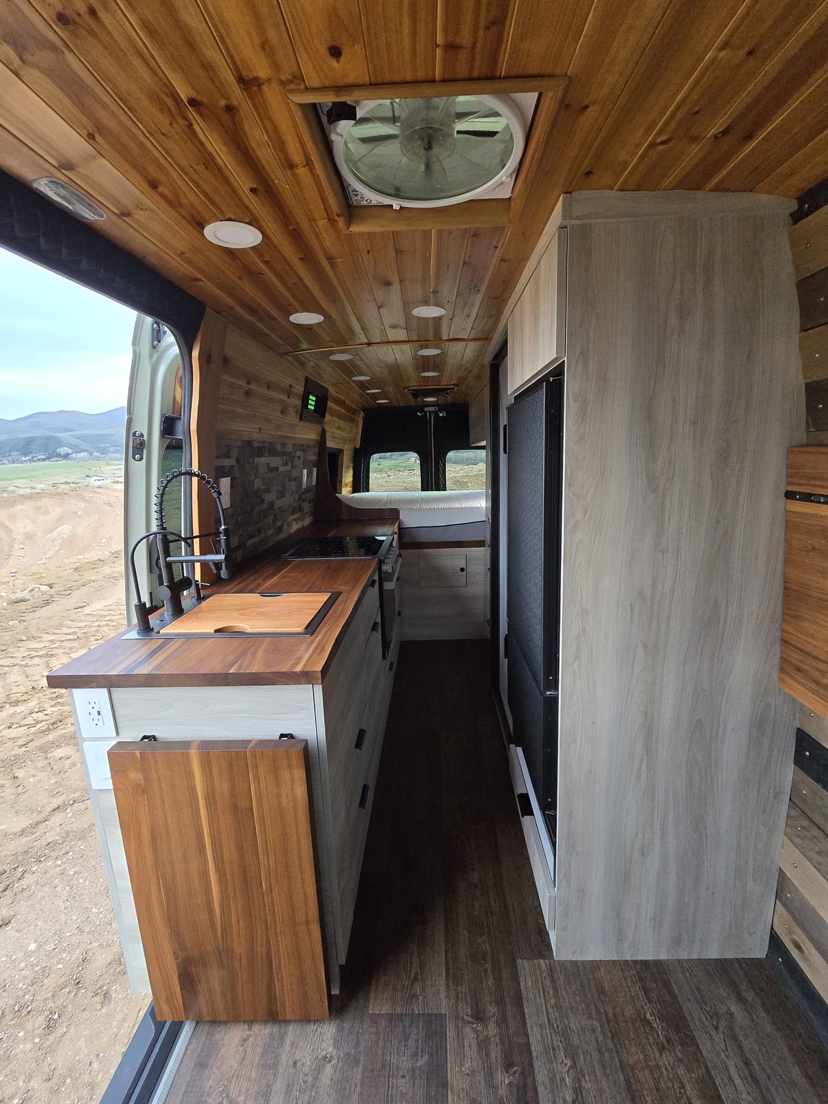 Custom camper van interior built by Kamas Valley Handyman with walnut butcher-block counters, a cedar plank ceiling and custom cabinetry